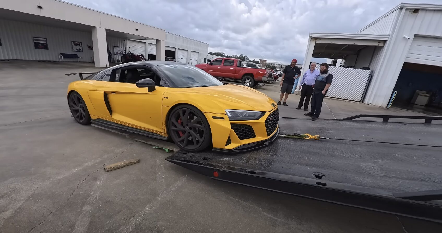 Yellow luxury sports car being loaded onto a professional flatbed tow truck